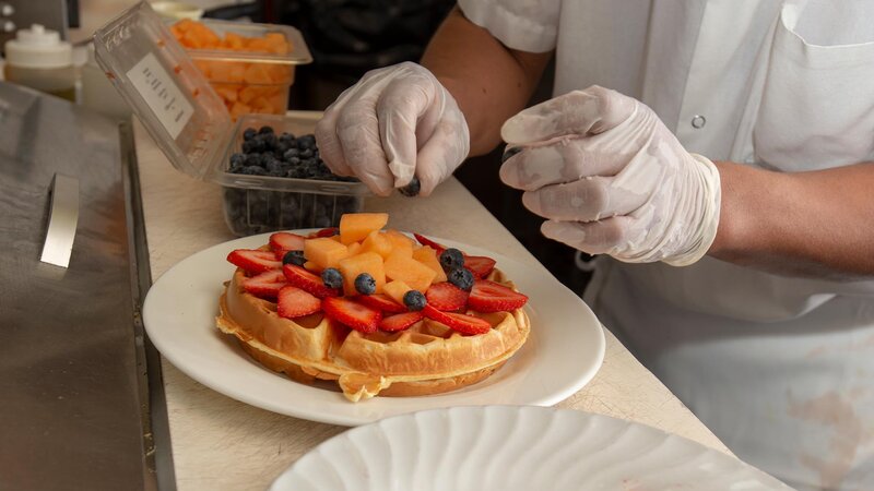 Chef placing fresh fruit on a waffle