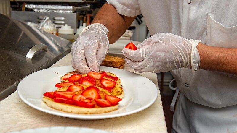 Kitchen staff placing strawberries on a waffle