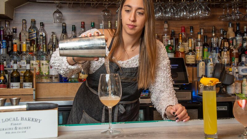 Bar tender pouring a cocktail into a wine glass