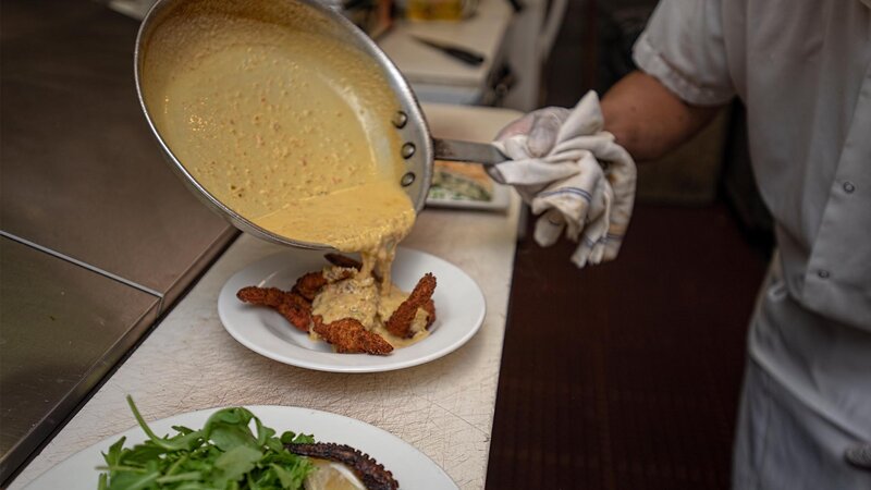 Chef pouring sauce on fried garlic shrimp