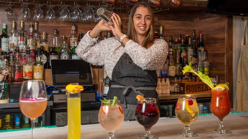 Bar tender shaking a cocktail with many cocktails in front of them