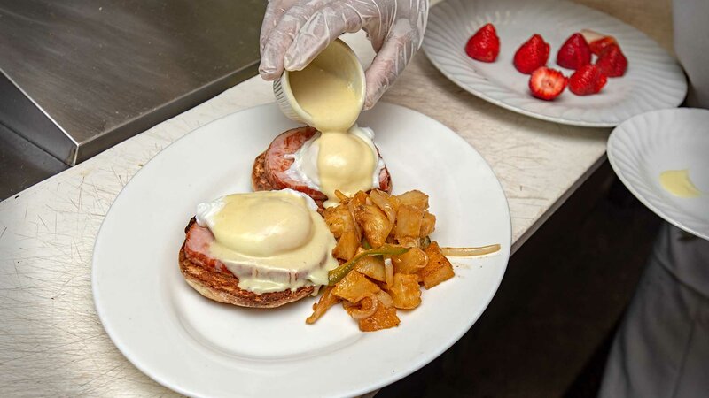 Kitchen staff preparing a taylor ham & cheese on a roll sandwich